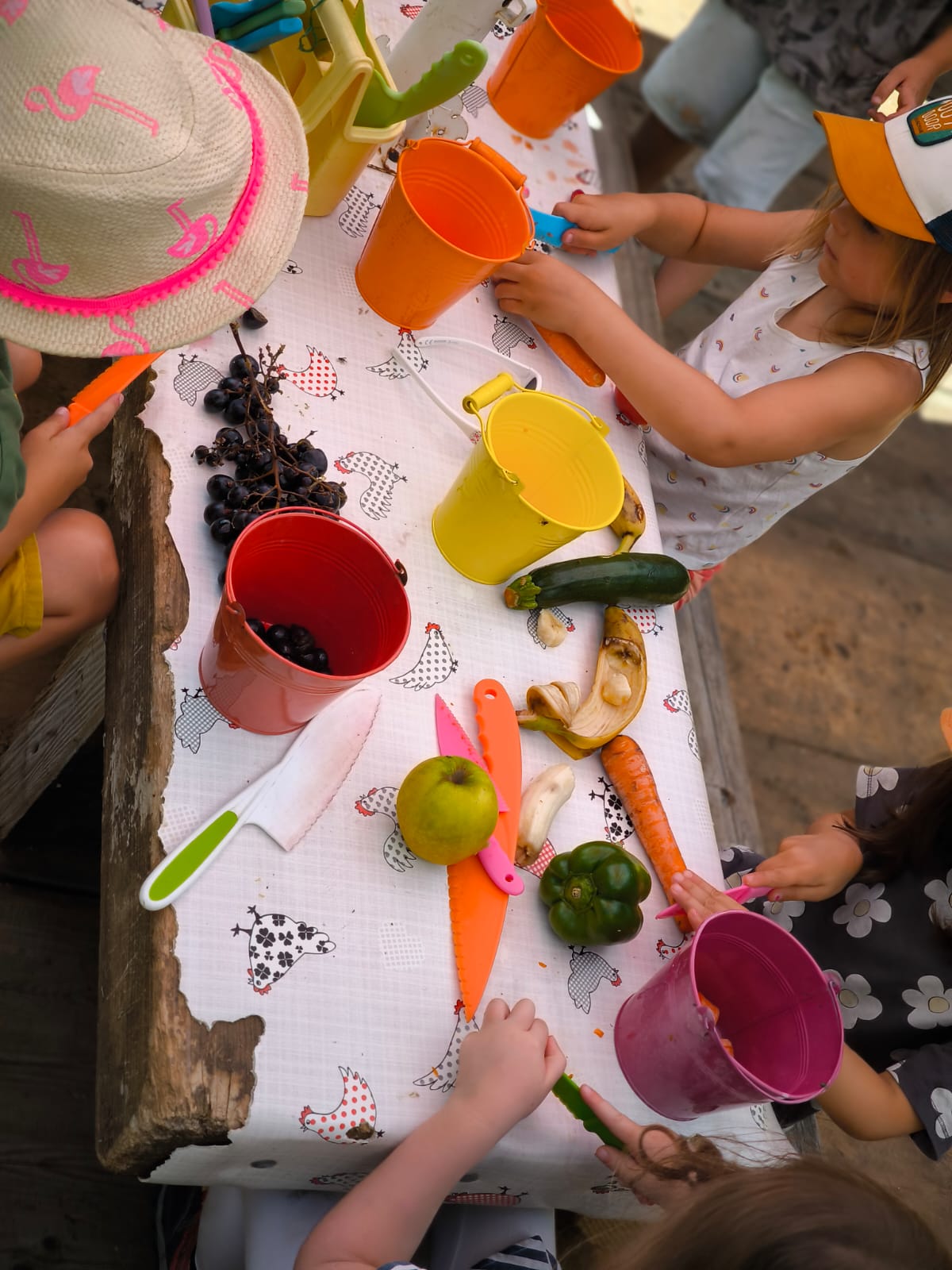 Des enfants autour d'une grande table en bois préparent fruits et légumes pour les animaux